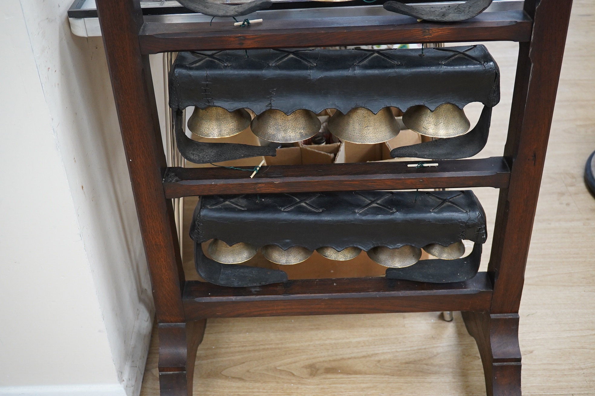 An early 20th century set of Swiss cow bells, four rows, mounted on an oak stand, 124 cm high. Condition - good